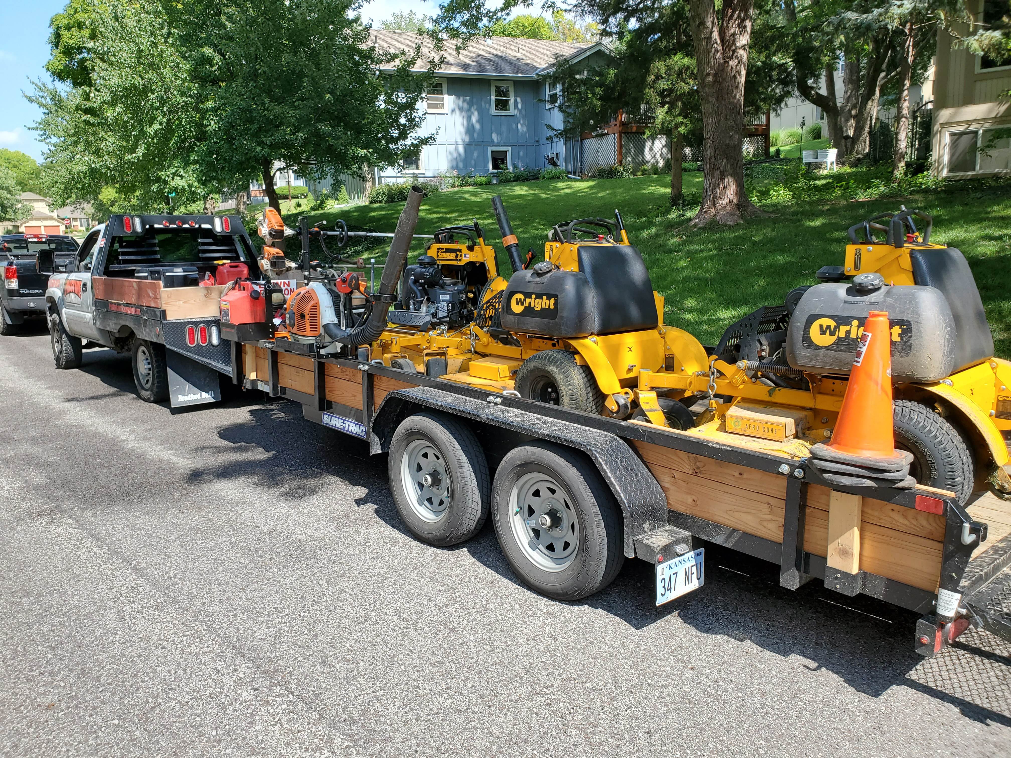 Pristine work truck and trailer loaded with Wright stand-on mowers and blowers